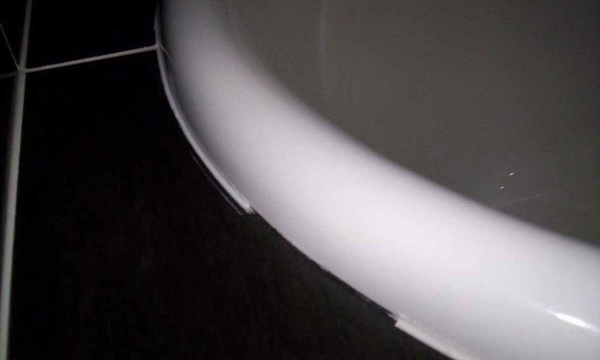The same curved bath lip after repair, the surface smooth and glossy with the chip gone.