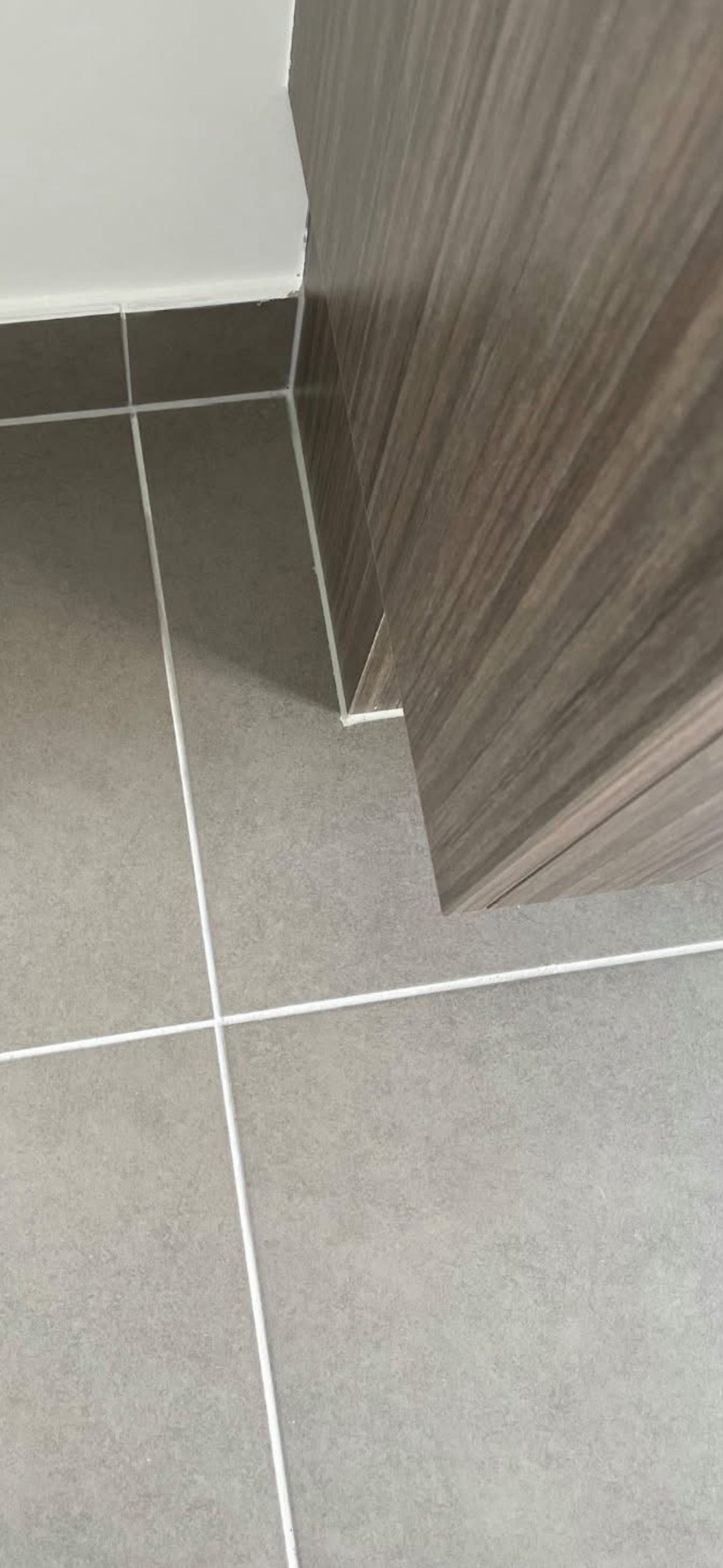 The same tiled floor after repair, the tile surface unbroken beside the kickboard.