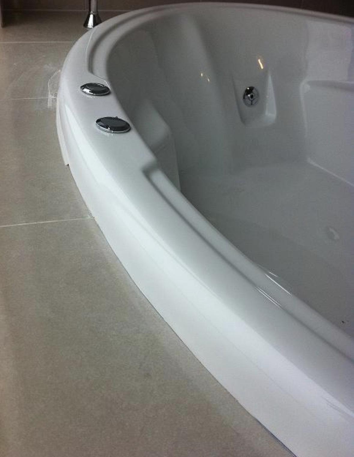 The same corner spa bath after repair, the rim running smooth and unbroken all the way round with no sign of the missing piece.