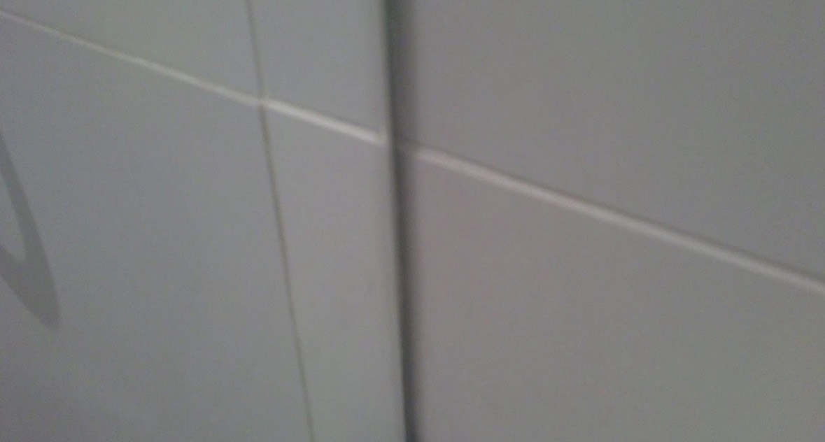 The same wall tile after repair, the grout line running straight and clean with no sign of the chip.
