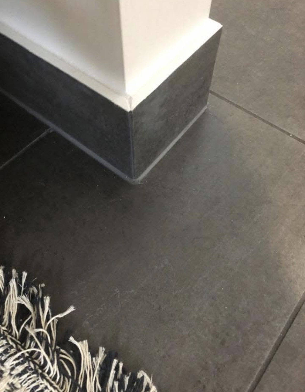 The same tiled corner after repair, the two tiles meeting in a tight clean line.